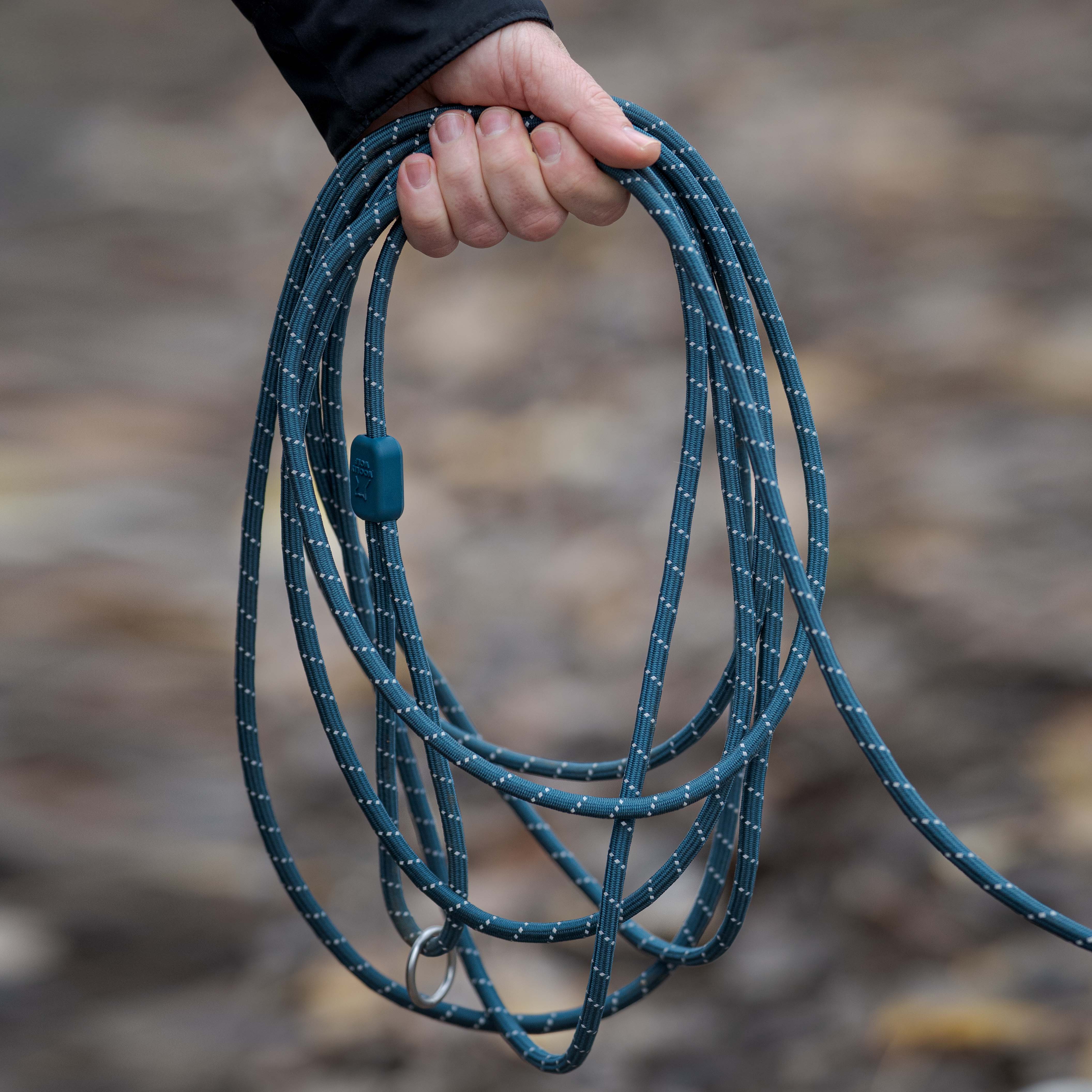 Hand holds coiled blue rope with white flecks and a metal ring.