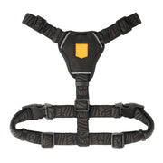 Black dog harness with a yellow logo patch and adjustable straps.